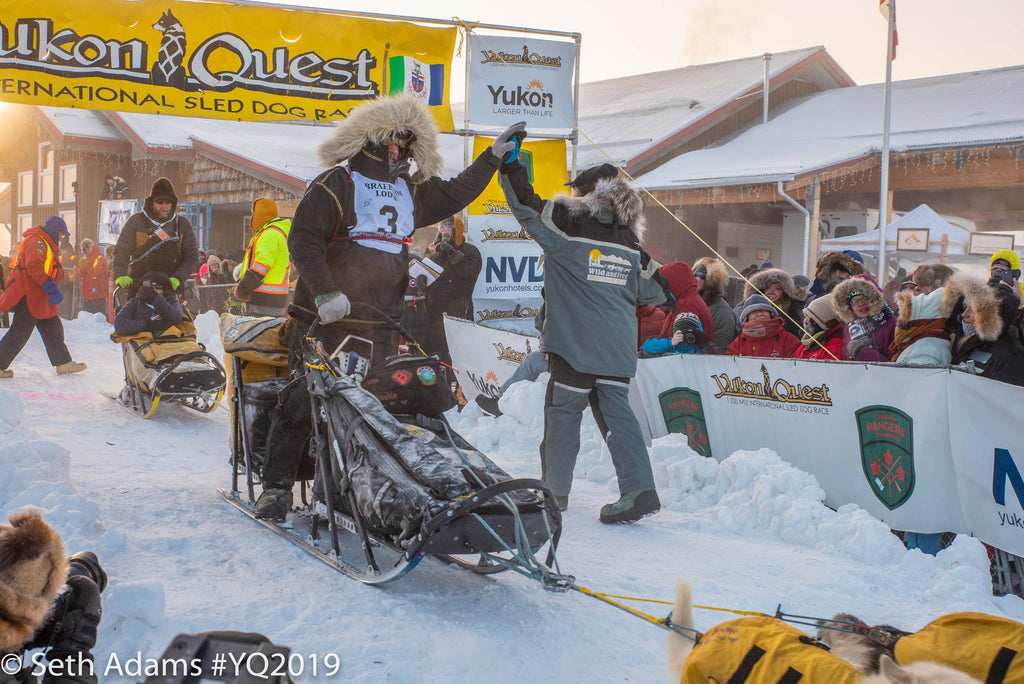 Brent at the start of 2019 Yukon Quest, sharing a high five with handler Steven Stoller.