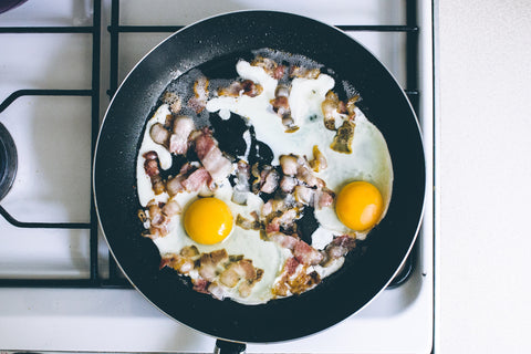 Bacon and eggs in a skillet.