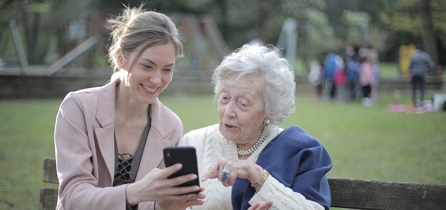 Woman with elderly mother looking at smartphone. Does cbd oil work for pain? How to use cbd oil for back pain. How long does it take for cbd oil to work for joint pain?