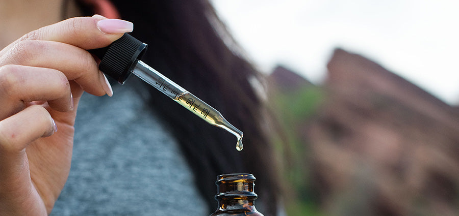 Woman with CBD drops in eye dropper. How long does it take for cbd oil to work for joint pain?