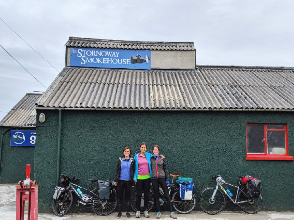 Fiona, Lucy and friend standing outside a building in Stornoway with their bikes