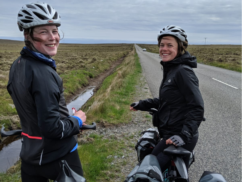 Fiona and friend on bikes looking back at camera in Scottish countryside