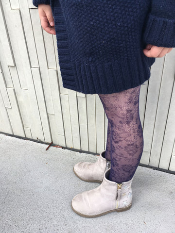 A young girls' legs displaying floral tights in a royal blue colour.