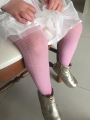 Close up of little girls lower legs wearing pink tights.