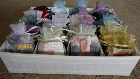 Shallow storage box with four rows of hosiery neatly displayed in organza bags.