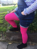 Girl standing with one foot on a step, hands in pockets and wearing fuchsia coloured tights.