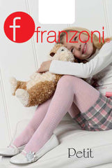Young girl sitting with knees up and left arm resting across her knees clutching a brown and cream soft toy puppy . She is wearing a long sleeved white top, pink, white and grey check shorts, rose pink houndstooth tights with white flat shoes.