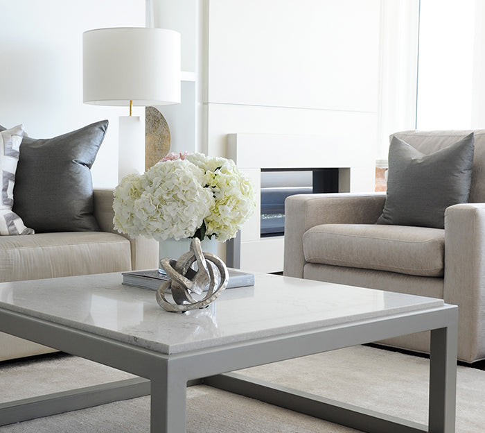 Modern living room with chairs, grey coffee table, and white fireplace in the background