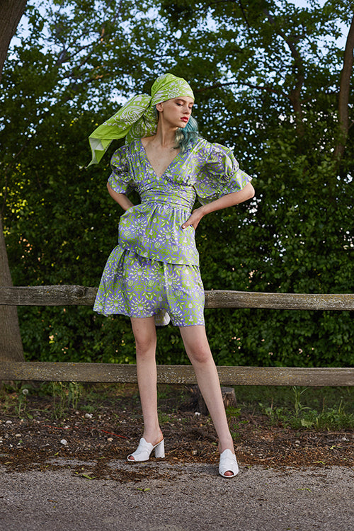 Cynthia Rowley 2019 Resort Collection features a floral printed dress with a plunging neckline, belted high waist, and tiered bottom. 