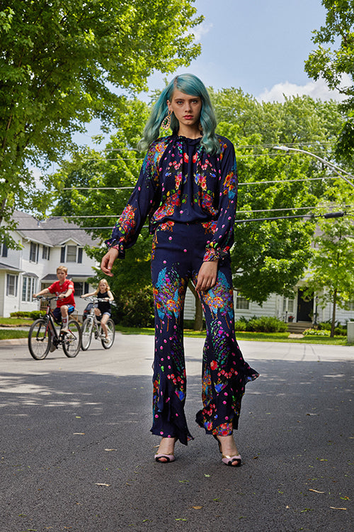Cynthia Rowley Resort 2019 Collection showing a floral navy jumpsuit, bold earrings, and three-toned heels. 