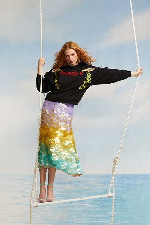 Cynthia Rowley Spring 2018 Look 33 featuring a ombre sequin skirt and black cotton sweatshirt with ‘love dove’ embroidered across front