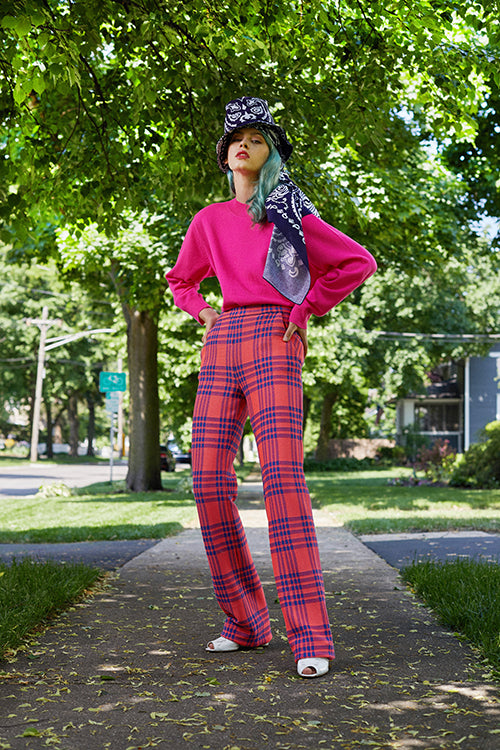 Cynthia Rowley Resort 2019 Collection features high waisted plaid pants worn with a bright pink sweater, and accessorized with a navy and white paisley hat and hair wrap.
