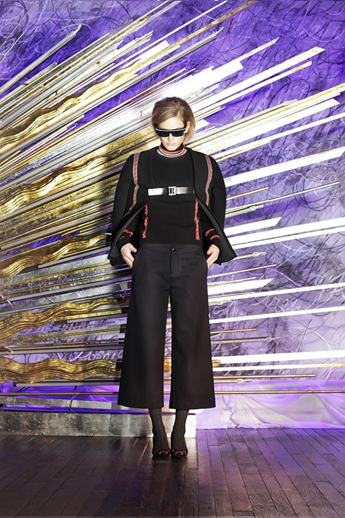 Cynthia Rowley Fall 2014 look 11 featuring a black long sleeve top with red black and white striped turtle neck and red applique on sleeves with a black coat with red applique stripe and buckle detail with black flared pants