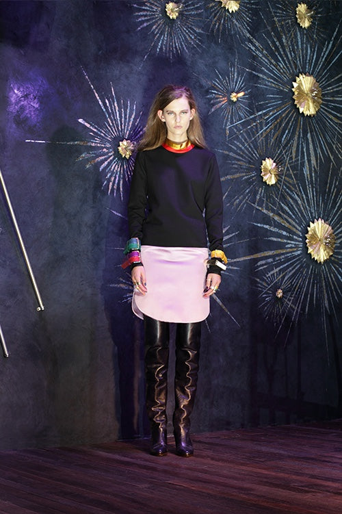 Cynthia Rowley Fall 2014 look 27 featuring a navy sweatshirt with yellow pink and blue buckles at the edge of the sleeves with a red neckline and a white mini skirt