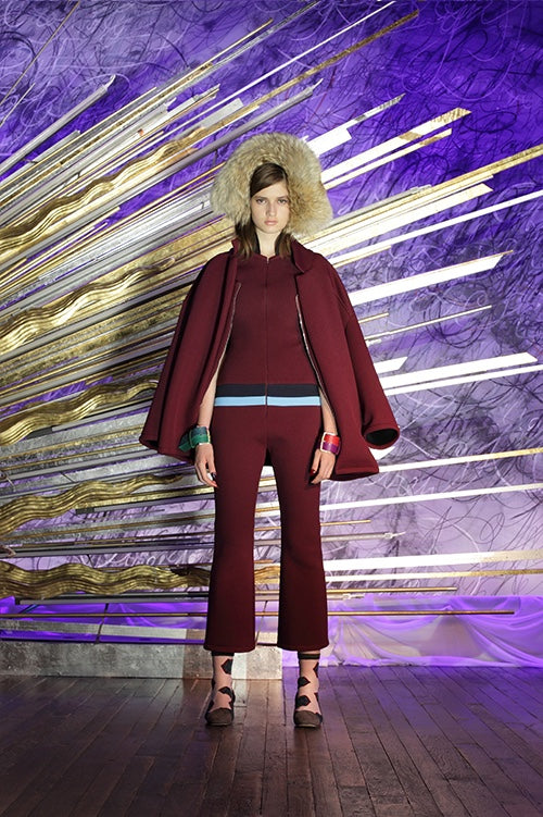 Cynthia Rowley Fall 2014 look 5 featuring a burgundy ankle length jumpsuit with navy and sky blue stripe detail at waist with a burgundy coat worn over the shoulders