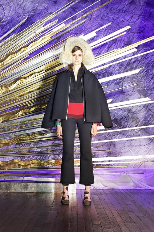 Cynthia Rowley Fall 2014 look 7 featuring a black v neck top with red stripe at the bottom with a black coat hanging and black ankle length pants