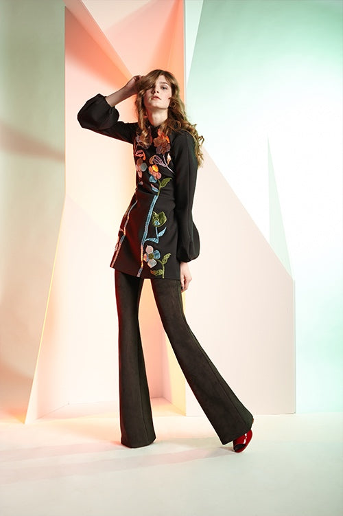 Cynthia Rowley Fall 2016 look 6 featuring a bell sleeve black wool crepe dress with rainbow metallic appliqués worn over black bonded suede flare pants