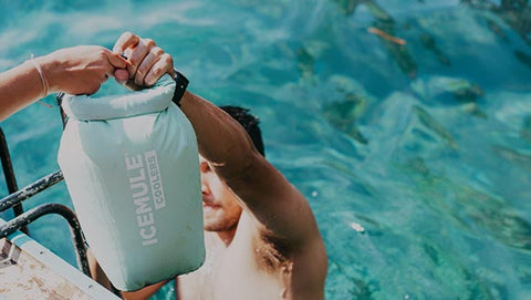 People pass their IceMule cooler out of the pool. 
