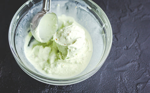 Homemade ice cream sits in a glass bowl on a countertop.