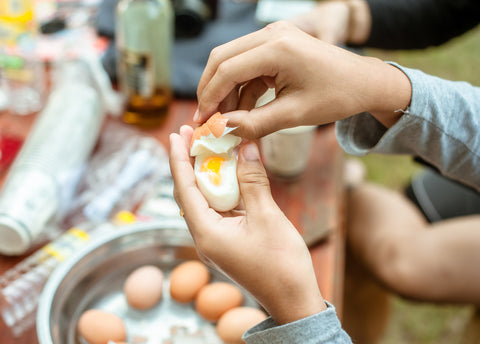 A person peels a hard-boiled egg.