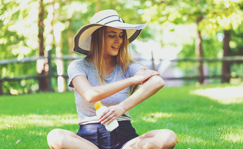 A woman applies sunscreen while she's sitting outside. 