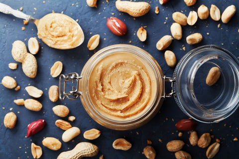 Peanuts surrounding a peanut butter jar make a healthy roadtrip snack.