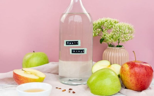 Selbstgemachte Apfel Rinse in einer Glasflasche vor einem rosa Hintergrund