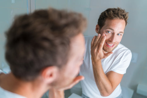 man applying face wash in mirror