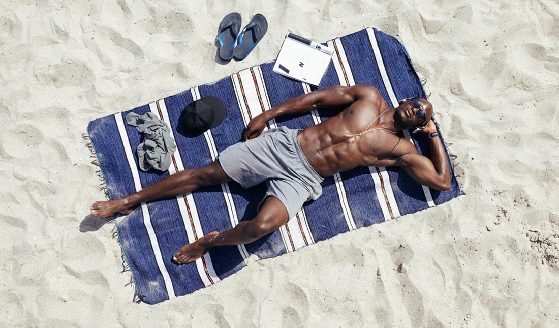 man lying on beach towel