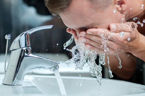 man rinsing face with water