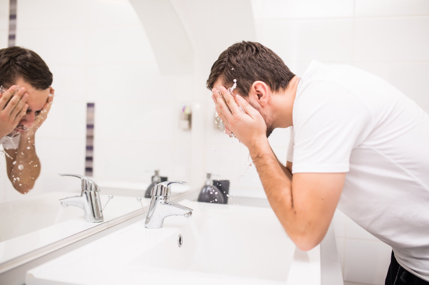 Man splashing water on his face over the bathroom sink