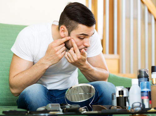 man squeezing pimple with fingers