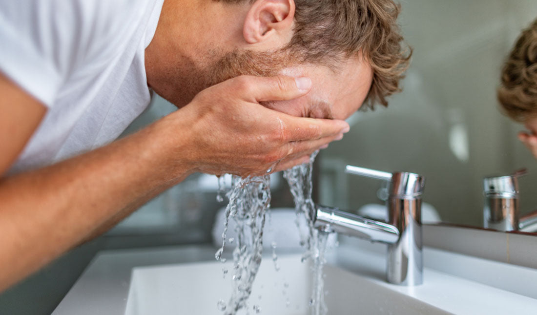 man washing face over sink