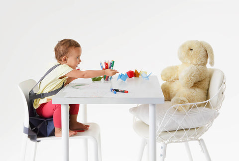 Little girl sitting at the table with coloring activity and a toy bunny. 