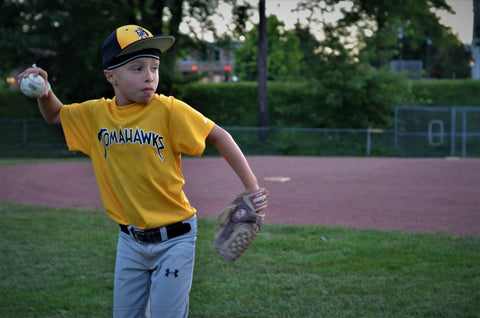 Young boy in baseball uniform throwing ball while wearing  protective headwear - 2nd Skull Skull Cap