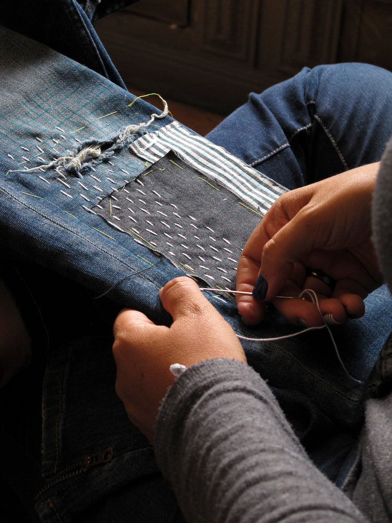 person mending a pair of jeans 