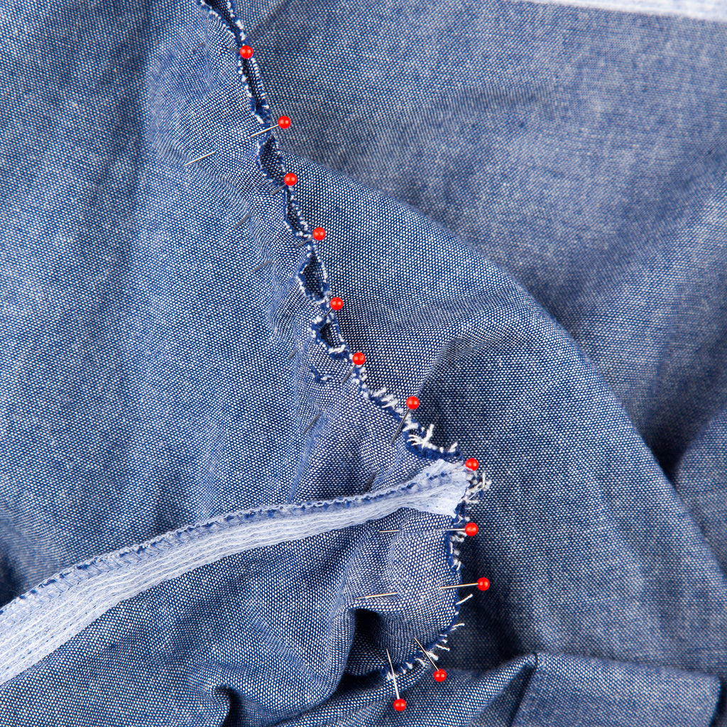 red pins on denim fabric holding seams together