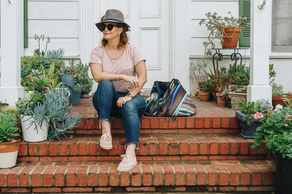 model sitting on brick steps with a new day lace up espadrille sneaker hat sunglasses and frayed cropped jeans