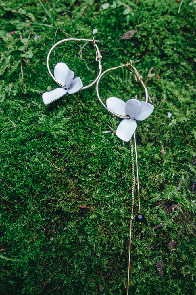 white flower asymmetrical hoop earrings on green plants
