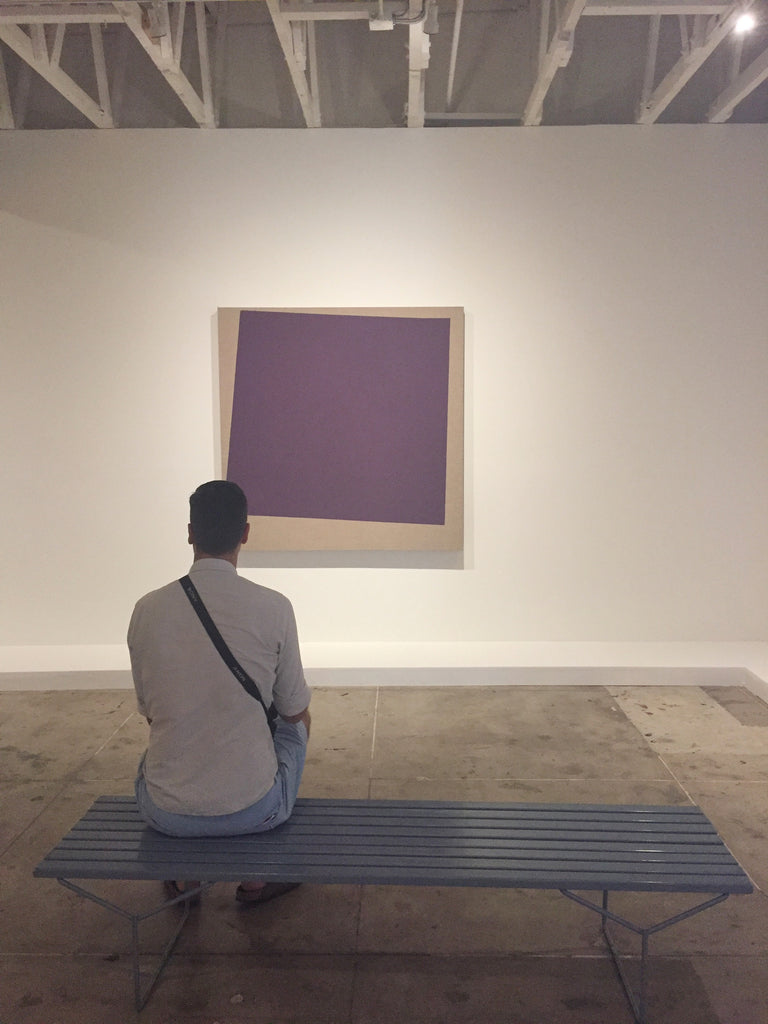 man sitting and looking at Noah Davis purple square painting at Underground Museum LA