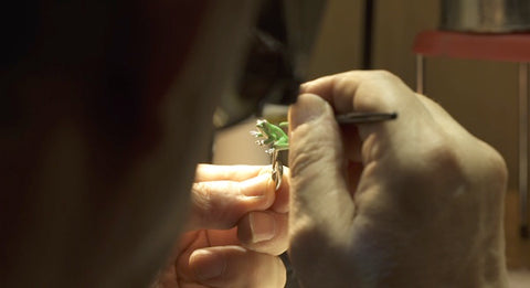 artisan painting a cufflink by hand with enamel