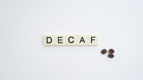 Scrabble letters spelling Decaf next to coffee beans