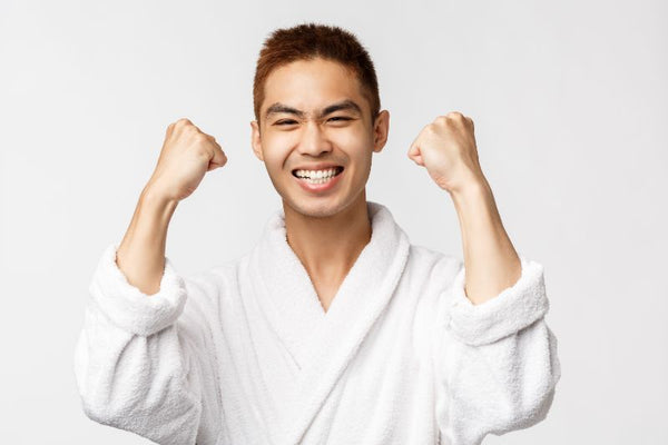man in white robe smiling in victory after his manzilian wax