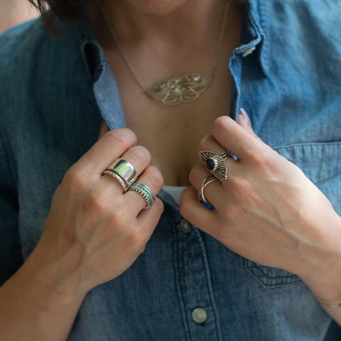 Christine Alaniz Designs stacks of rings on model with blue button down shirt