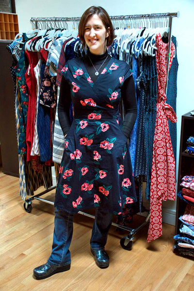 April wearing the Oberlin Dress in Pixel Rose over a black mock neck, blue jeans, and black clogs.