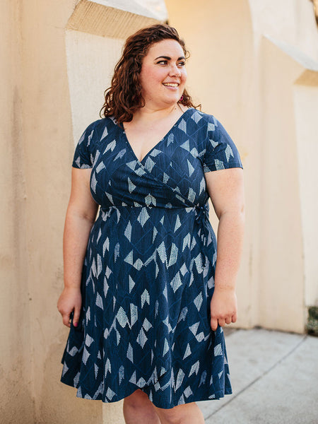 A plus-size model wearing the Ainslie Wrap Dress in Twilight. 