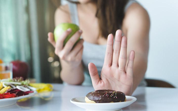 Woman saying no to sweet in the process of diet