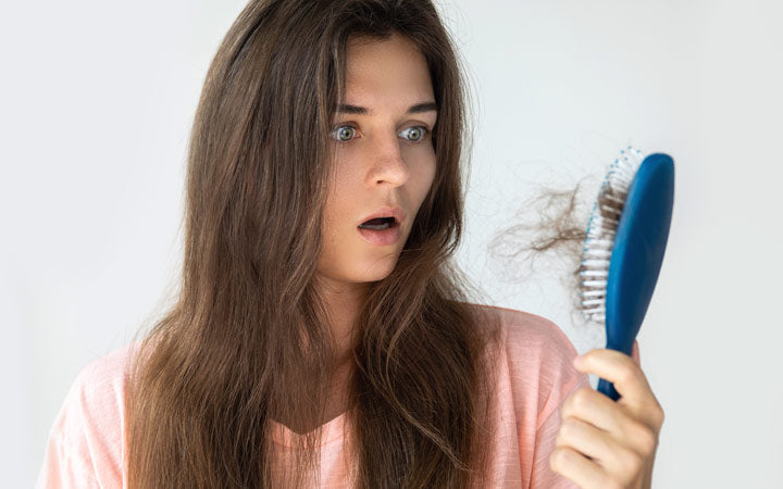 Woman holding hair comb and suprising about her hair loss