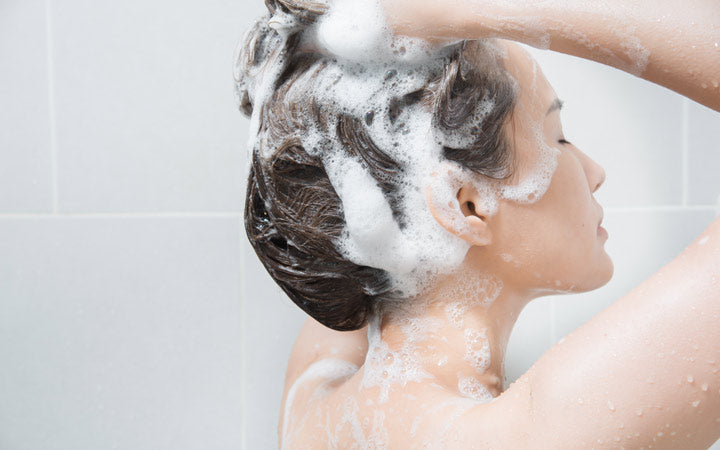 Woman washing her hair with shampoo