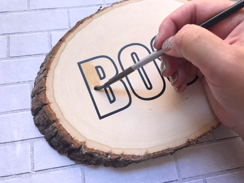 Painting using a brush inside kassa adhesive vinyl on wooden slice